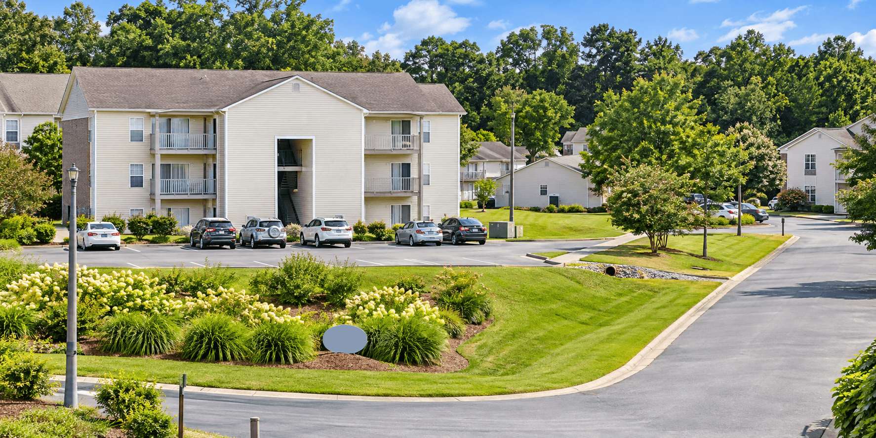 Apartment complex with a parking lot in front.